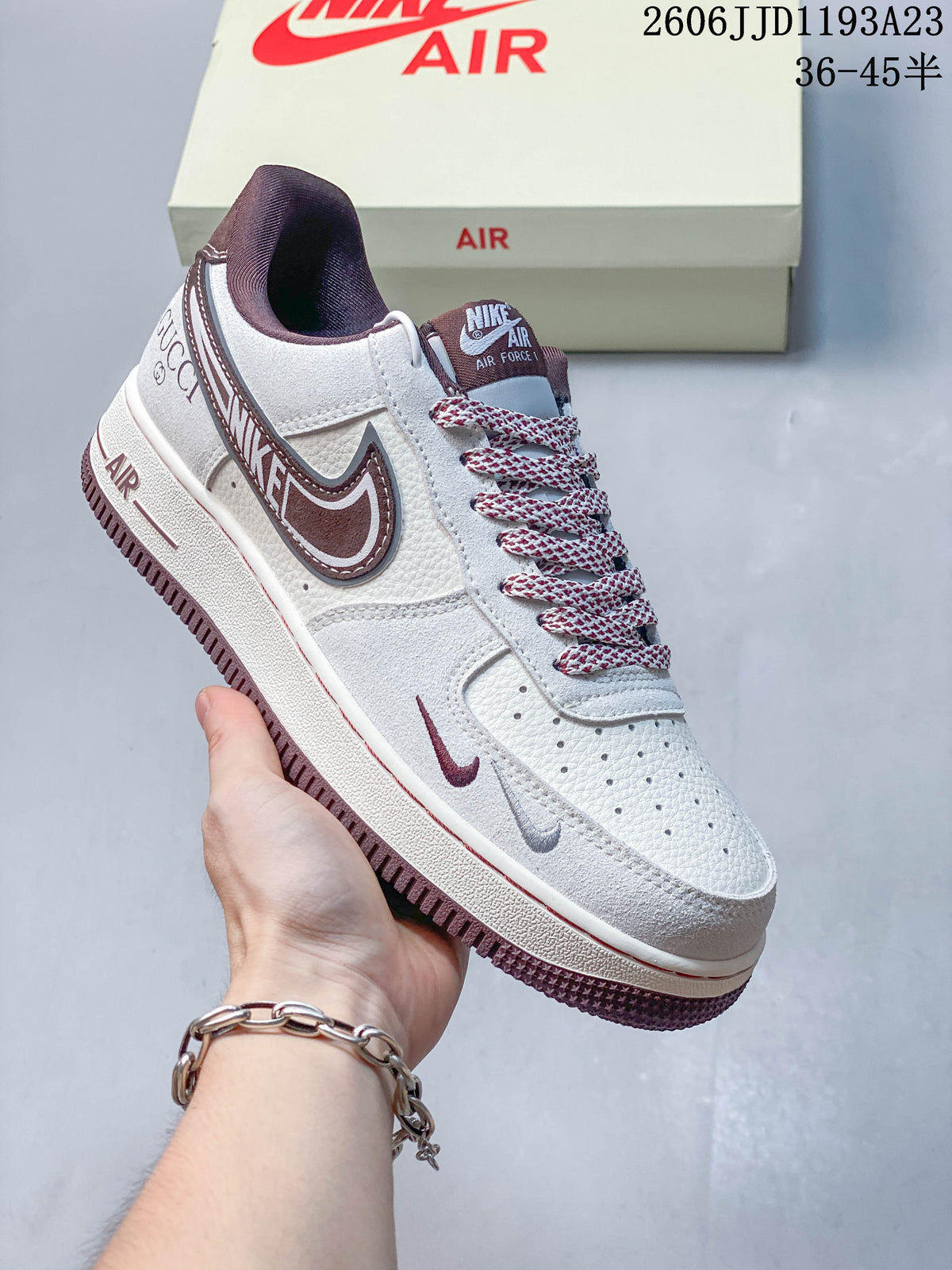 Close view of a white sneaker with burgundy Swoosh and heel detailing