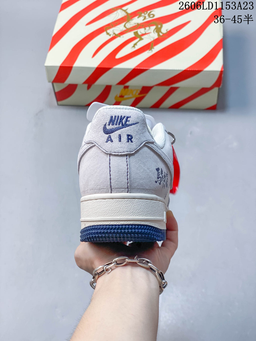 Rear view of a pale gray sneaker with dark blue heel branding and outsole
