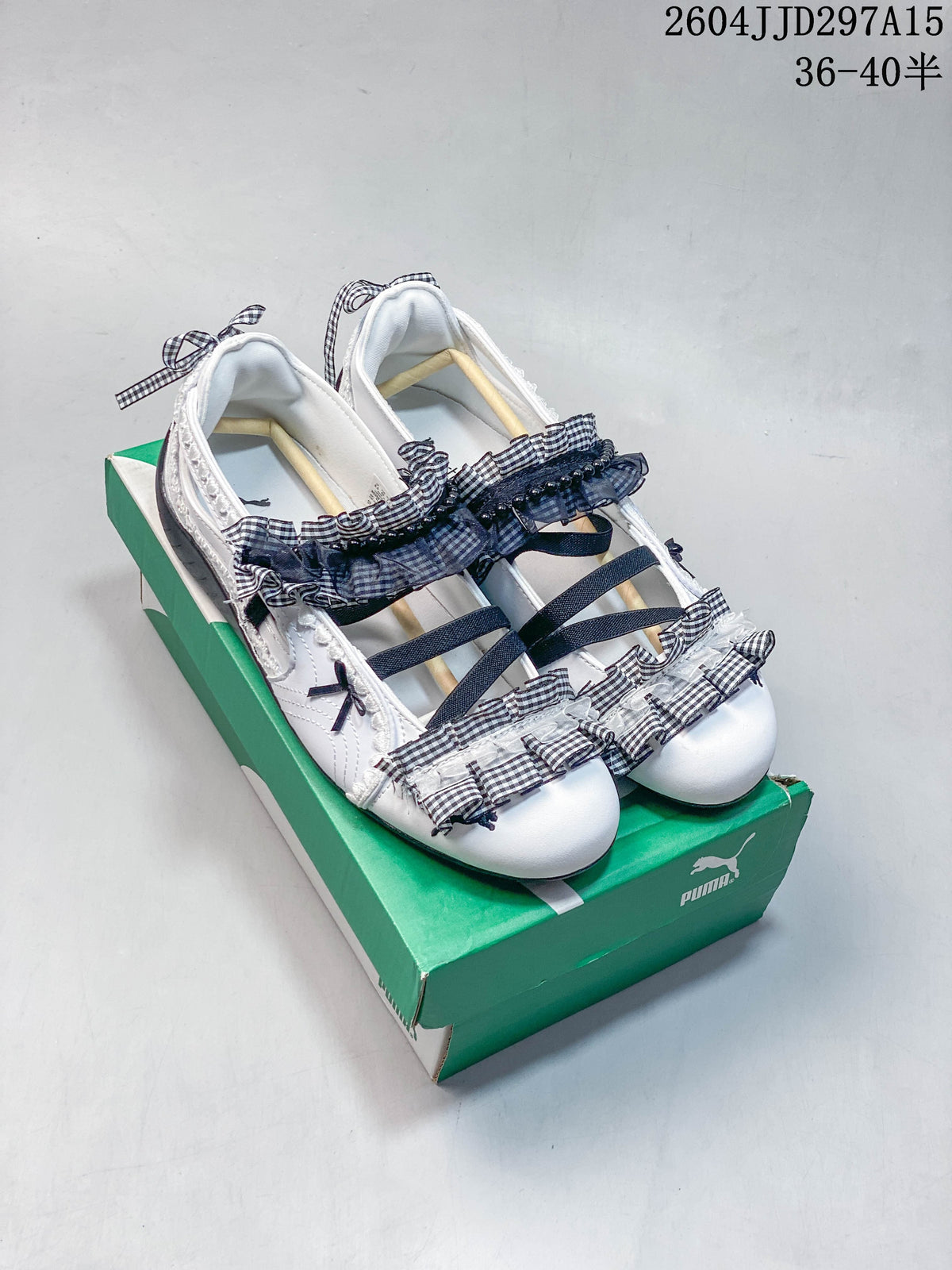 Pair of white Puma-branded flats with gingham ruffles and bows, shown on a green shoe box.