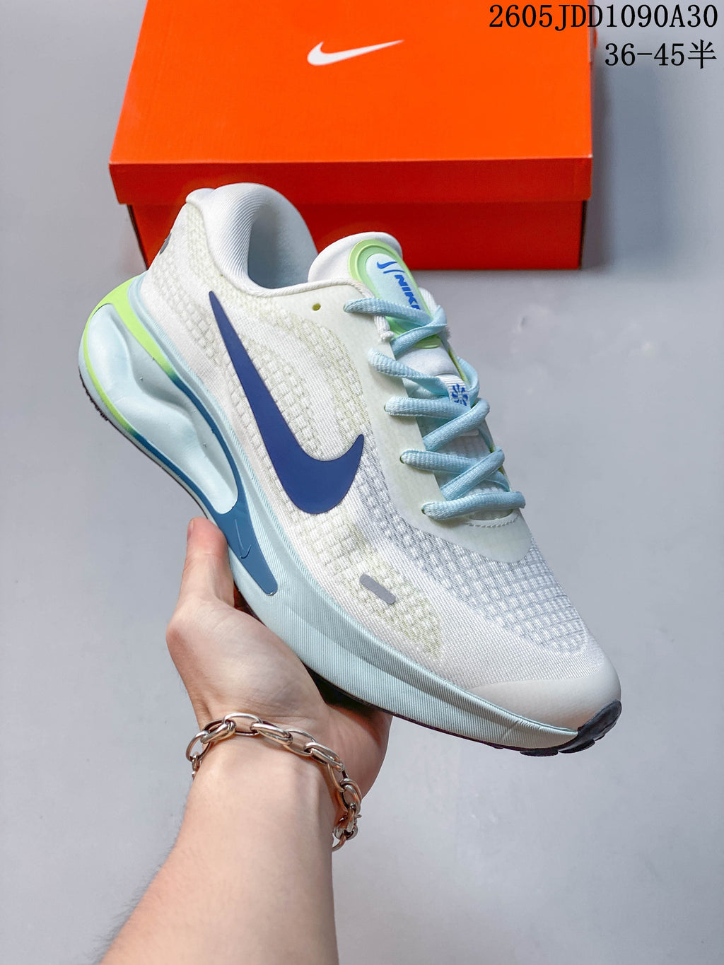 Angled side view of the white Nike Journey Run shoe with blue swoosh and sculpted midsole.