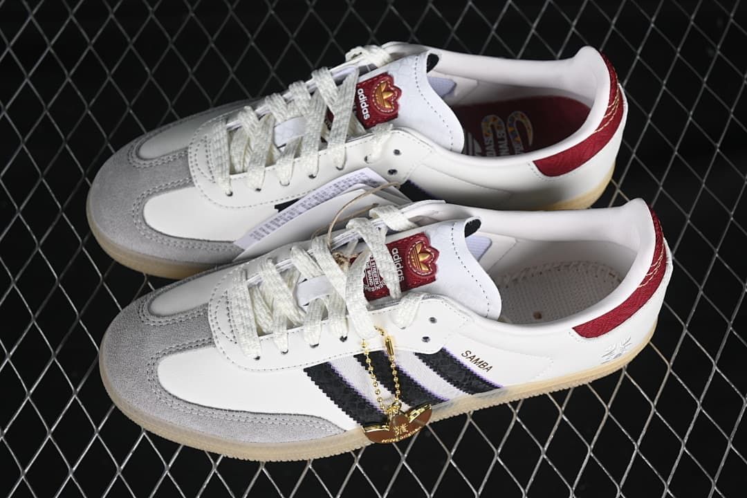 Pair of white Samba OG sneakers with black stripes and red accents displayed together