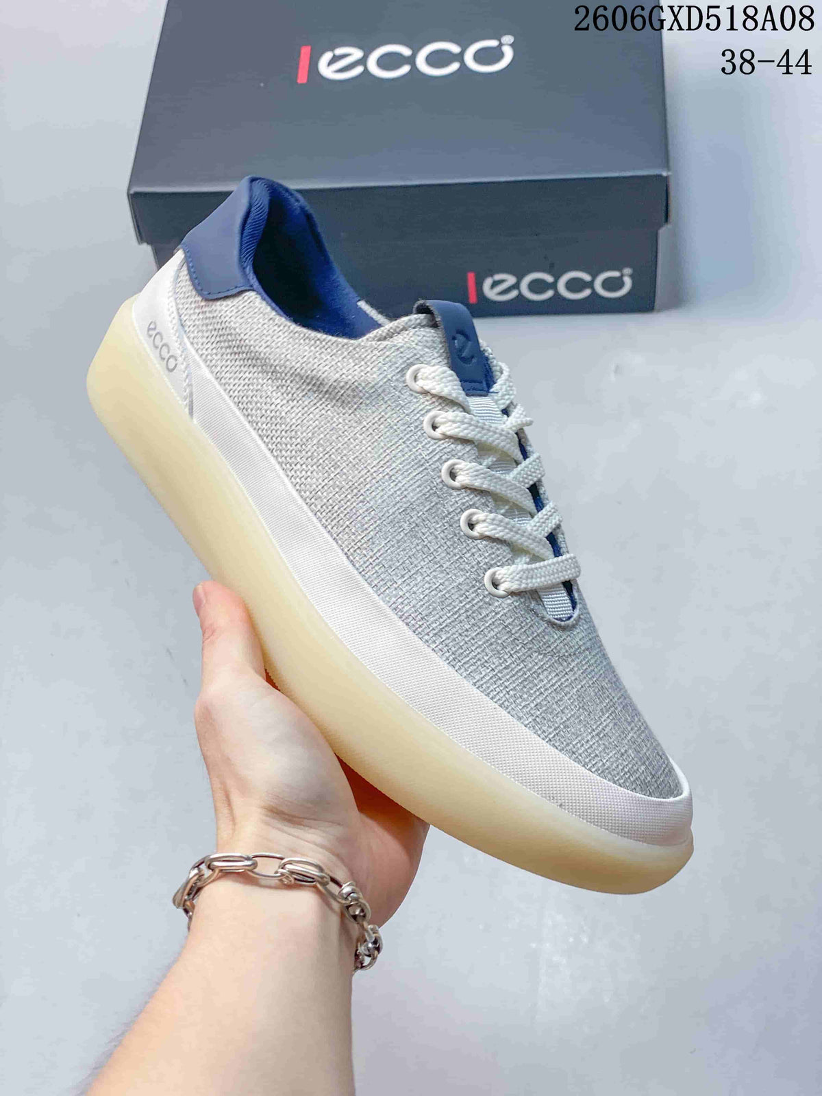 Angled side view of a gray low-top sneaker with white laces and navy accents.