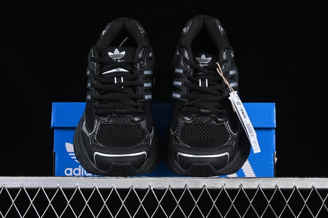 Front view of a pair of black sneakers with silver-toned details