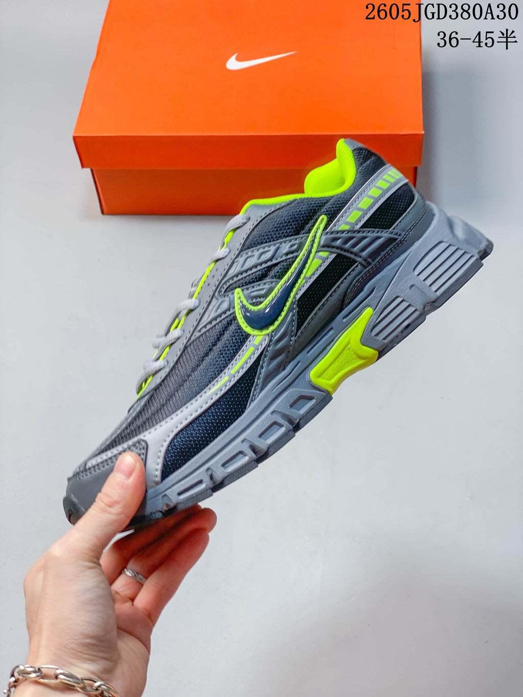 Side view of a gray and dark navy Nike sneaker with mesh panels and bright volt green details.