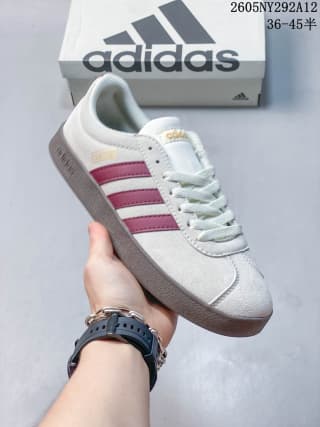 Angled close view of the off-white sneaker with burgundy stripes, laces, and padded collar.