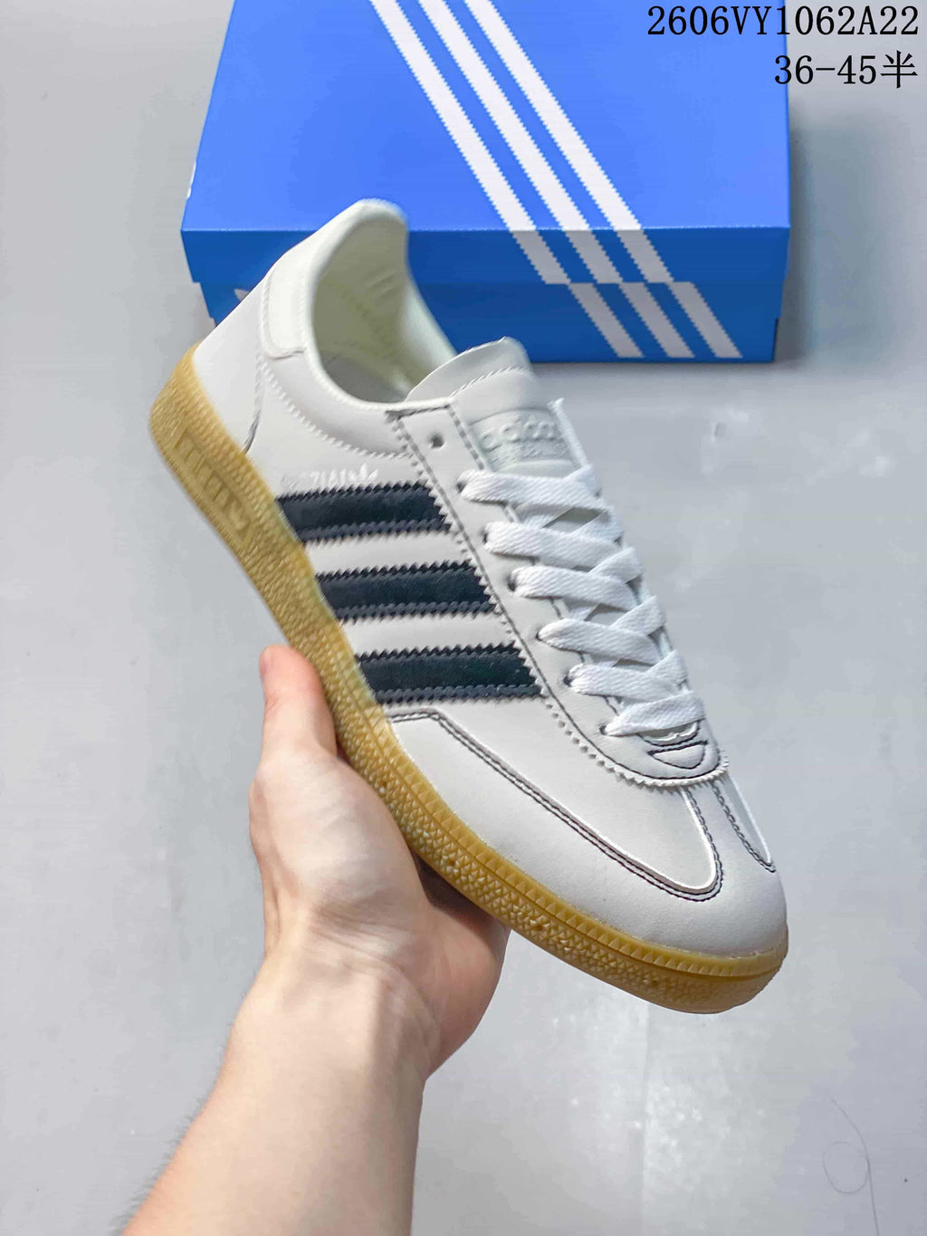 Angled view of the white Adidas Handball Spezial sneaker with navy stripes