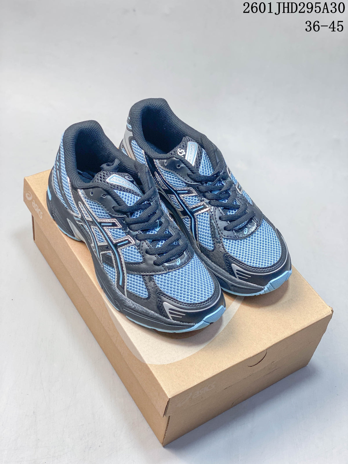 Pair of blue, silver, and dark gray ASICS GEL-Nimbus 10.1 sneakers on a shoebox
