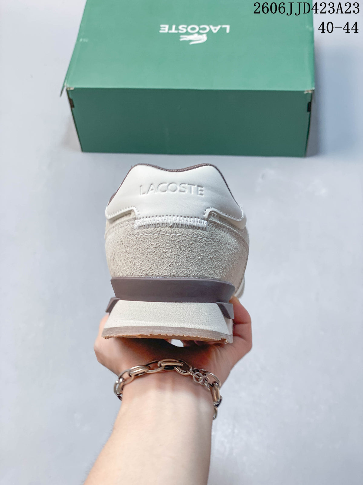 Rear view of the beige sneaker with a branded heel panel and layered midsole.