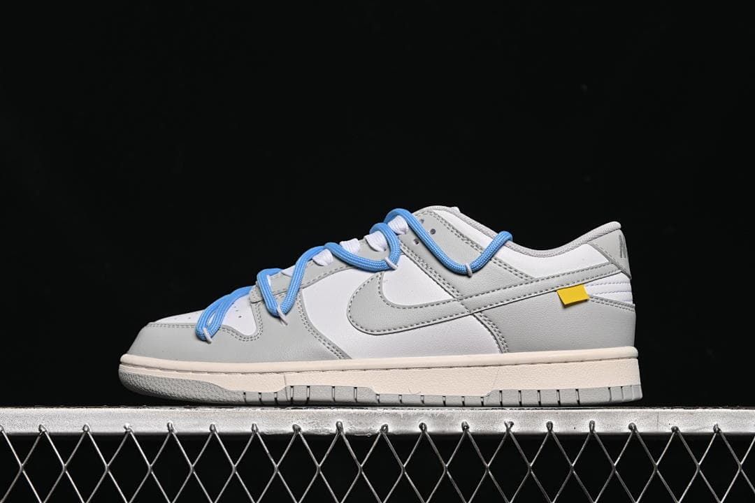 Side view of a white and grey Nike SB Dunk Low with blue overlay laces and a grey outsole