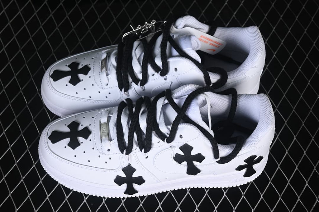 Pair of white low-top sneakers with black cross details and black laces.
