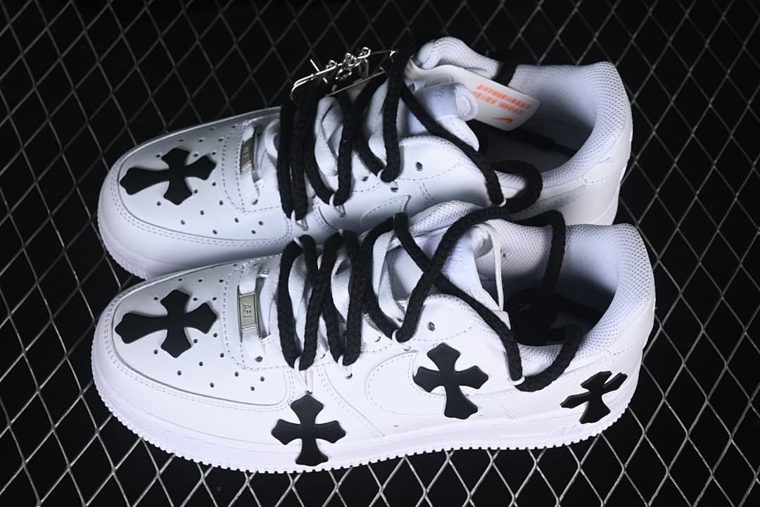 Pair of white low-top sneakers with black cross details and black laces.