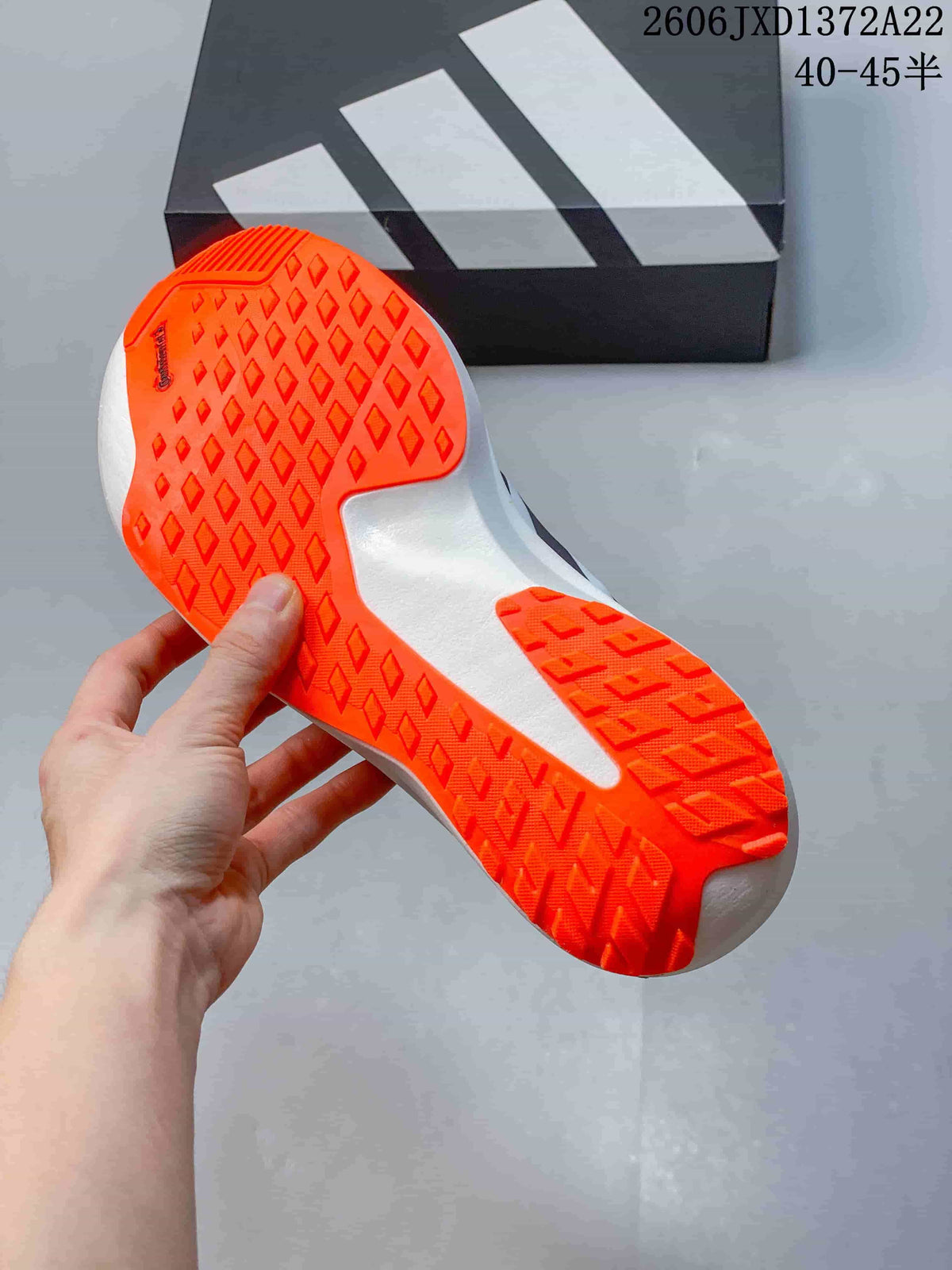 Close-up of the shoe outsole, showing bright orange patterned traction areas and a white midfoot section.
