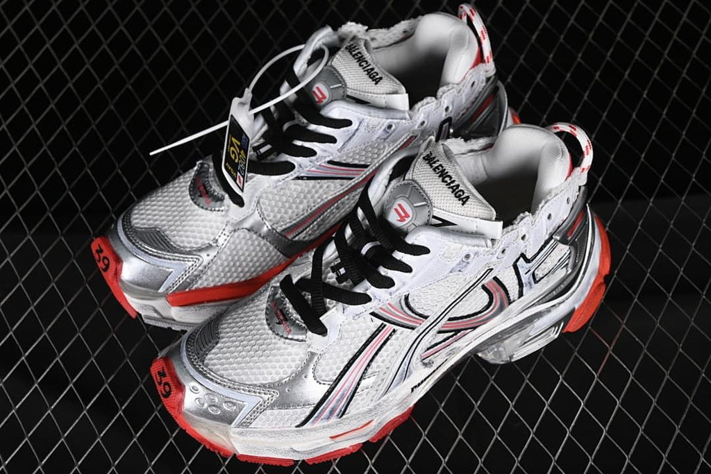 Pair of white and silver-toned sneakers with black laces and red accents.