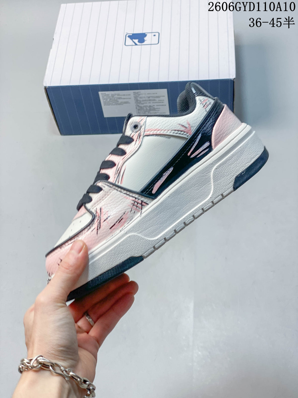 Side view of the white and pink low-top sneaker with graphic detailing