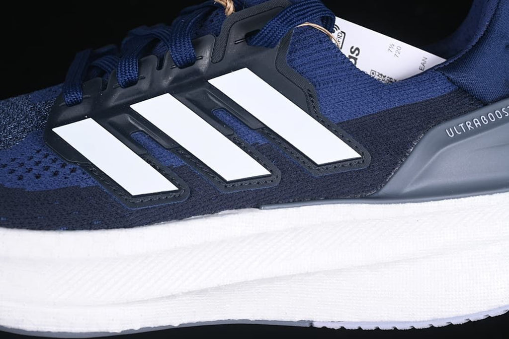 Close-up of the white three stripes, blue upper, laces, and gray heel detail.