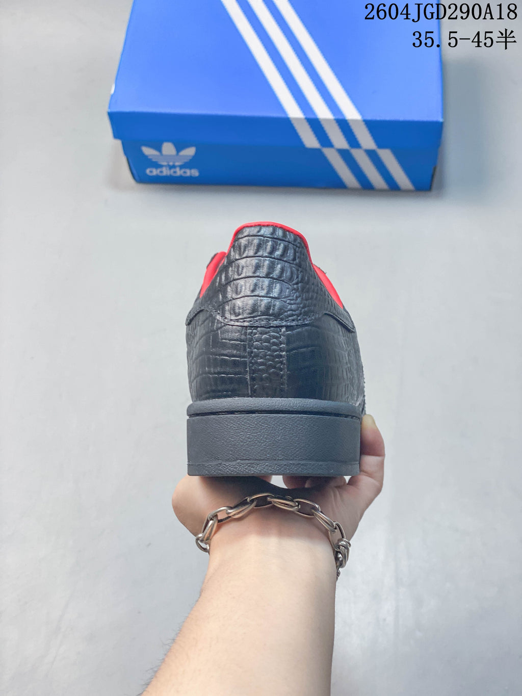 Rear view of the sneaker showing textured black panels, red lining, and a dark sole.
