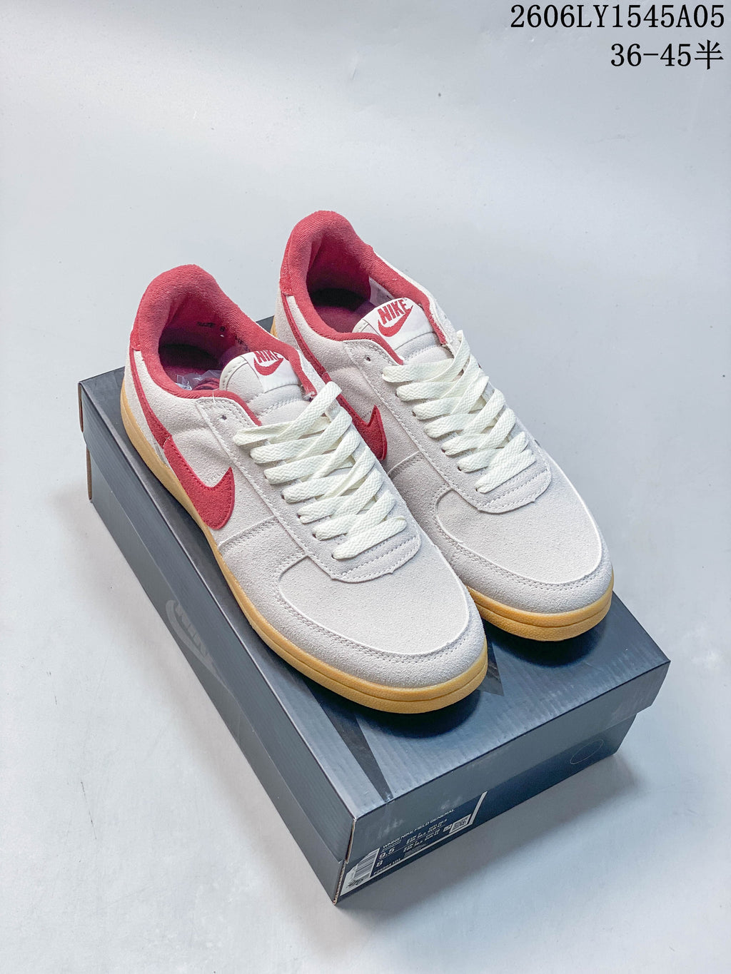 Pair of white low-top sneakers with red accents and gum-colored soles.