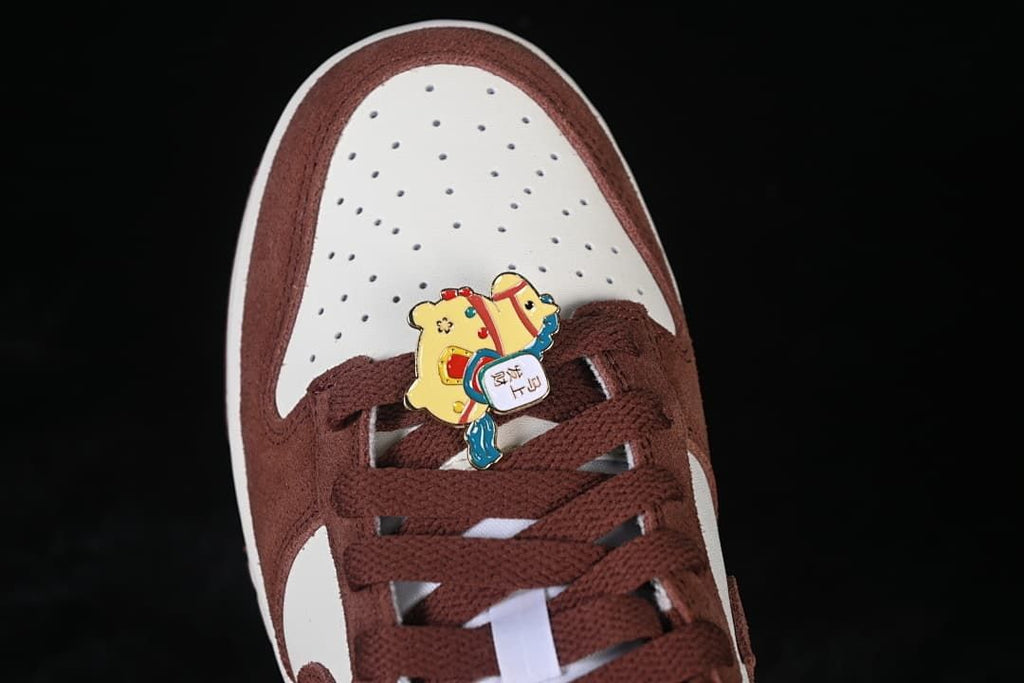 Top view of perforated white toe box, brown overlays, and horse-themed lace charm