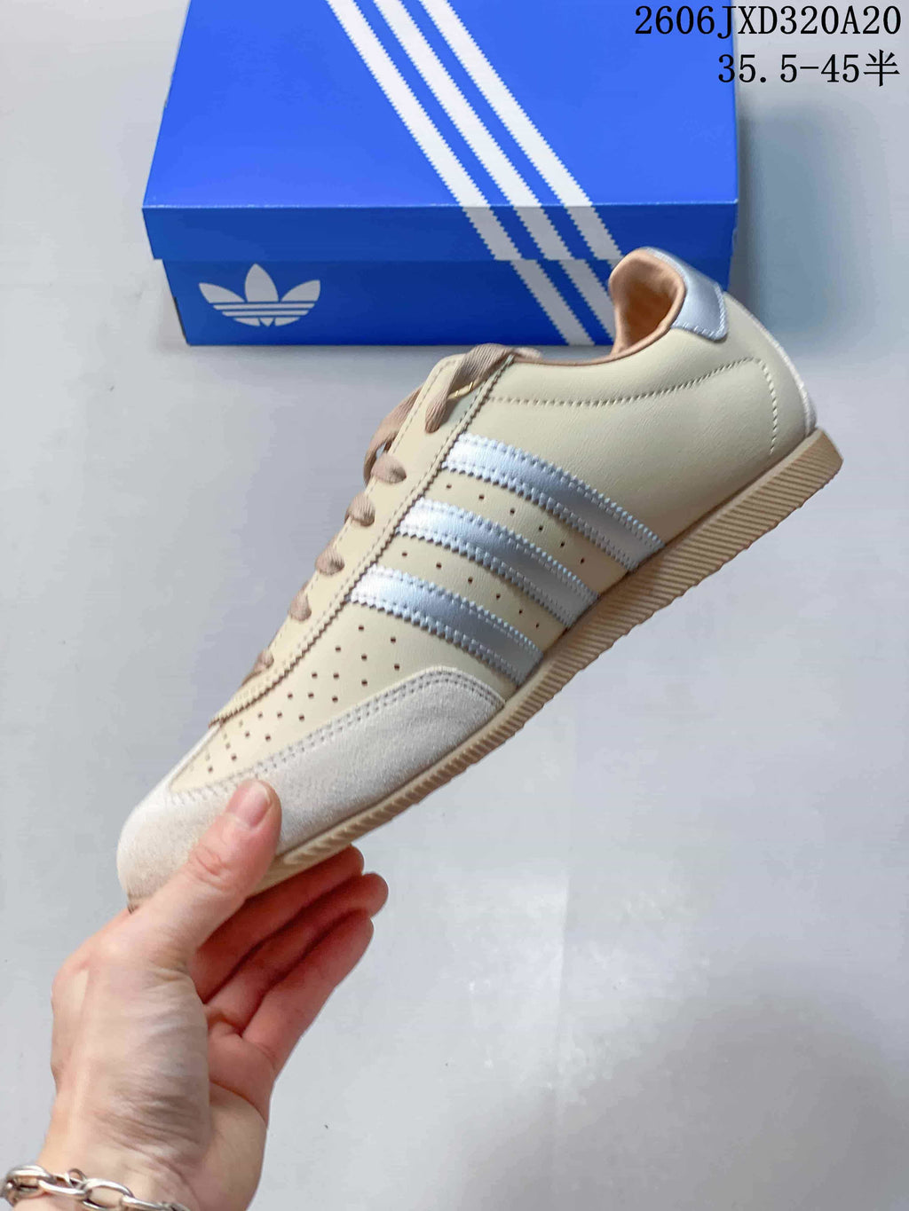 Side view of the beige sneaker with silver stripes, perforations and a gum-colored sole