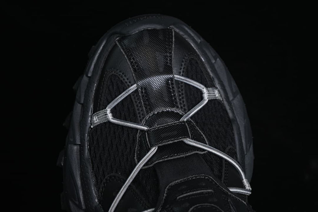 Top view of the black sneaker with cord lacing across the forefoot.