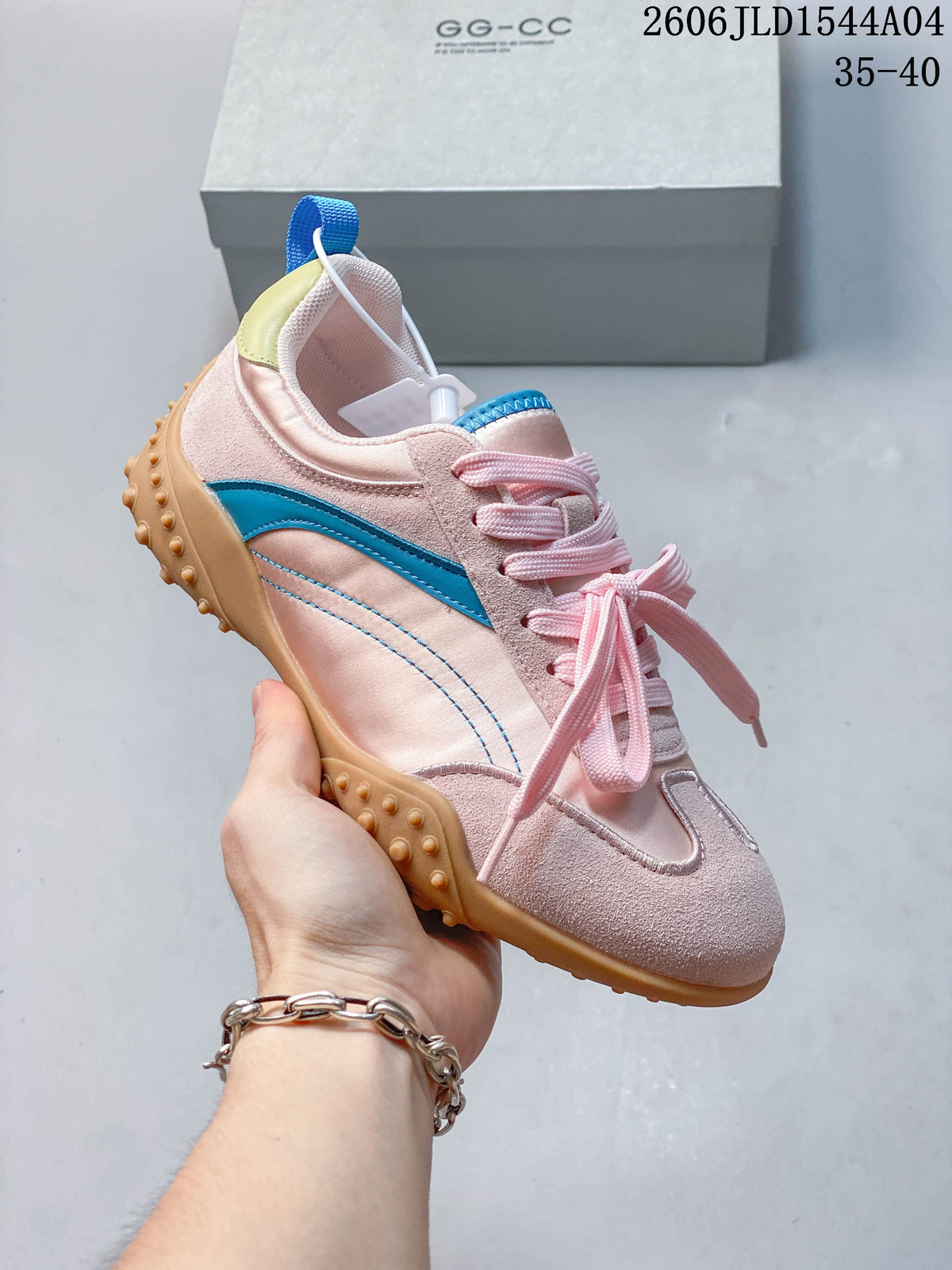 Angled side view of the pale pink sneaker with blue stripe, yellow heel detail, and tan outsole.