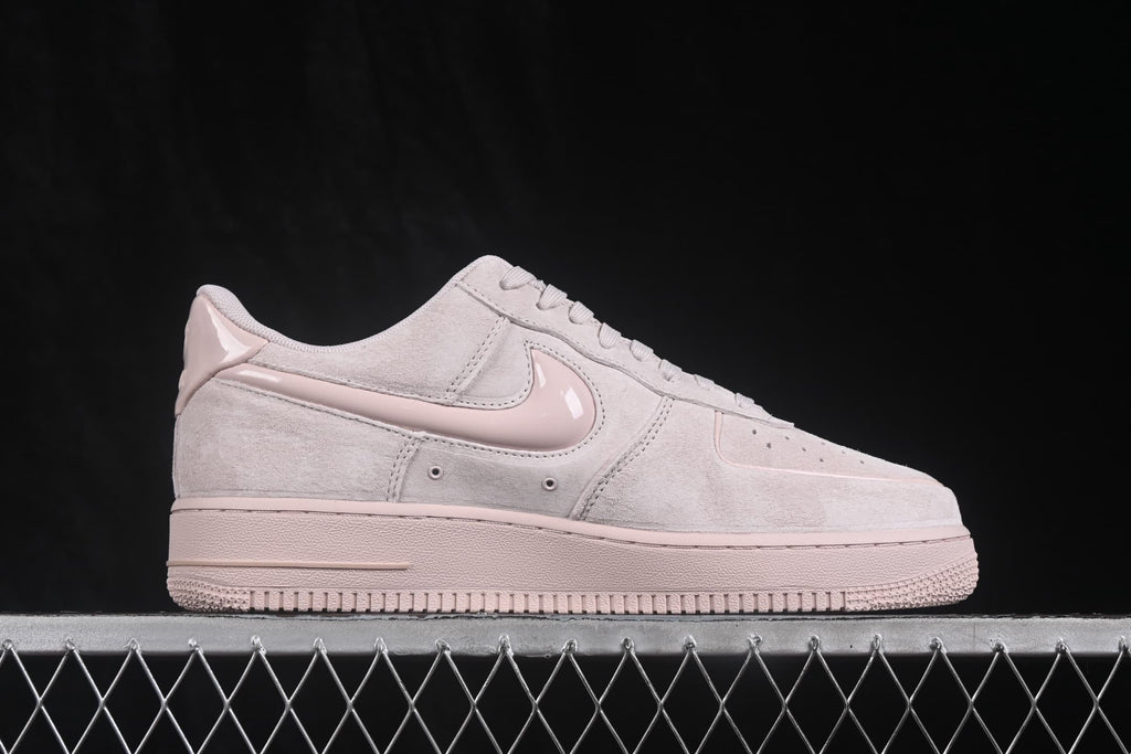 Side profile of the pale pink low-top sneaker showing the Swoosh, perforated toe area and Air midsole branding.