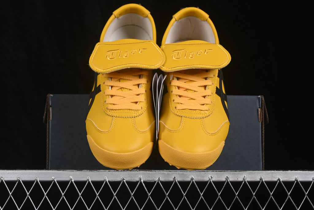 Front view of yellow Onitsuka Tiger sneakers with black accents and branded tongue flaps