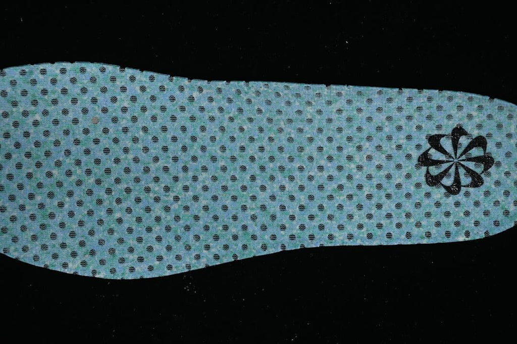 Reverse side of a blue perforated shoe insert with a small emblem.