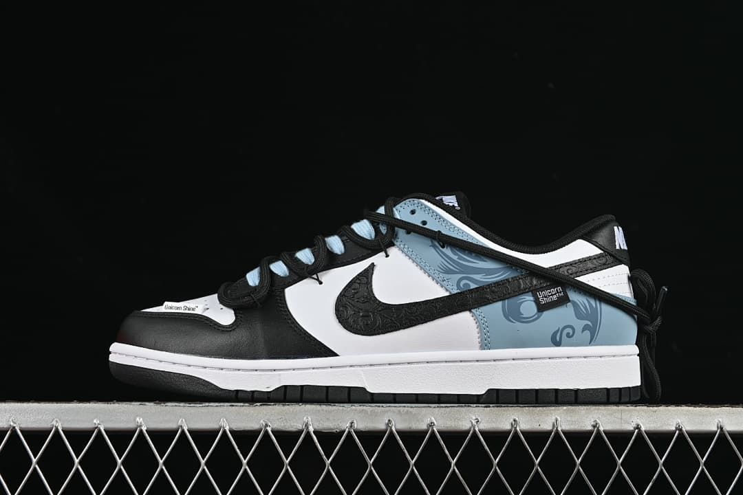 Side view of a black, white, and pale blue Nike SB Dunk Low with patterned overlays and contrasting laces.