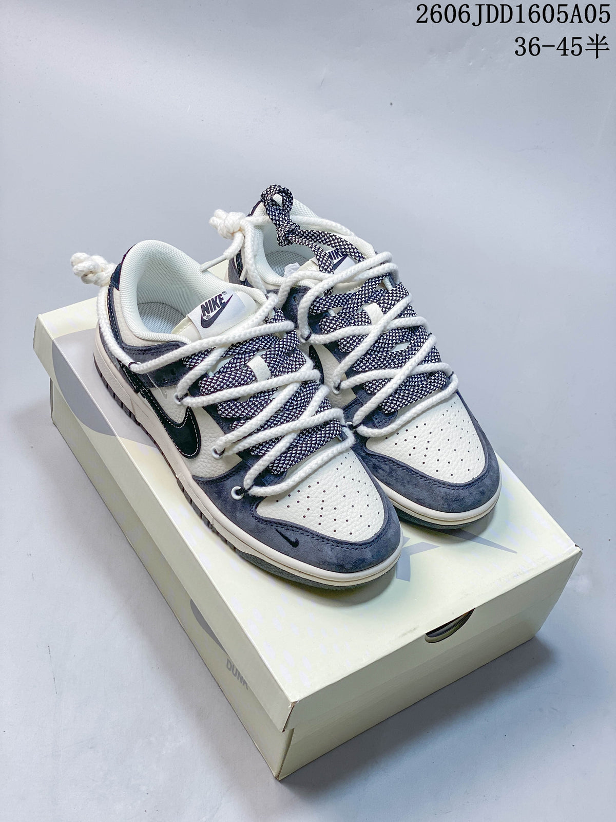 Pair of white, navy, and gray Nike SB Dunk Low sneakers on a box