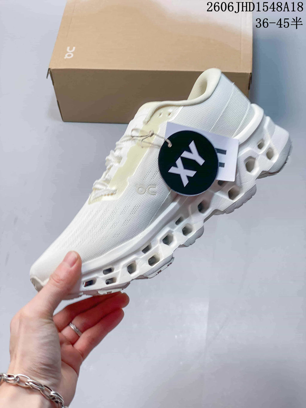 Side view of a white On Cloudmonster sneaker with a segmented sole
