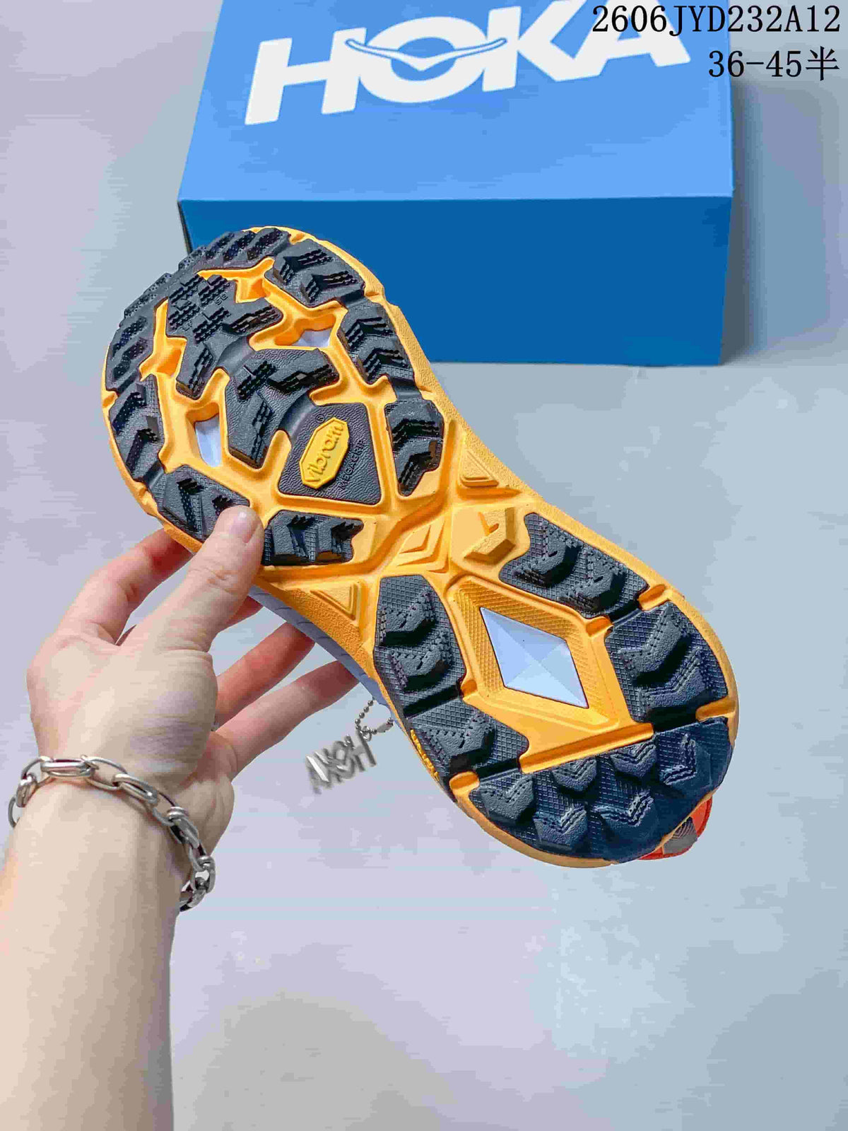 Underside view showing the lugged outsole of an orange HOKA shoe