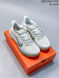 Pair of light gray and white Nike Pegasus 42 running shoes with muted green accents, displayed on an orange shoebox.