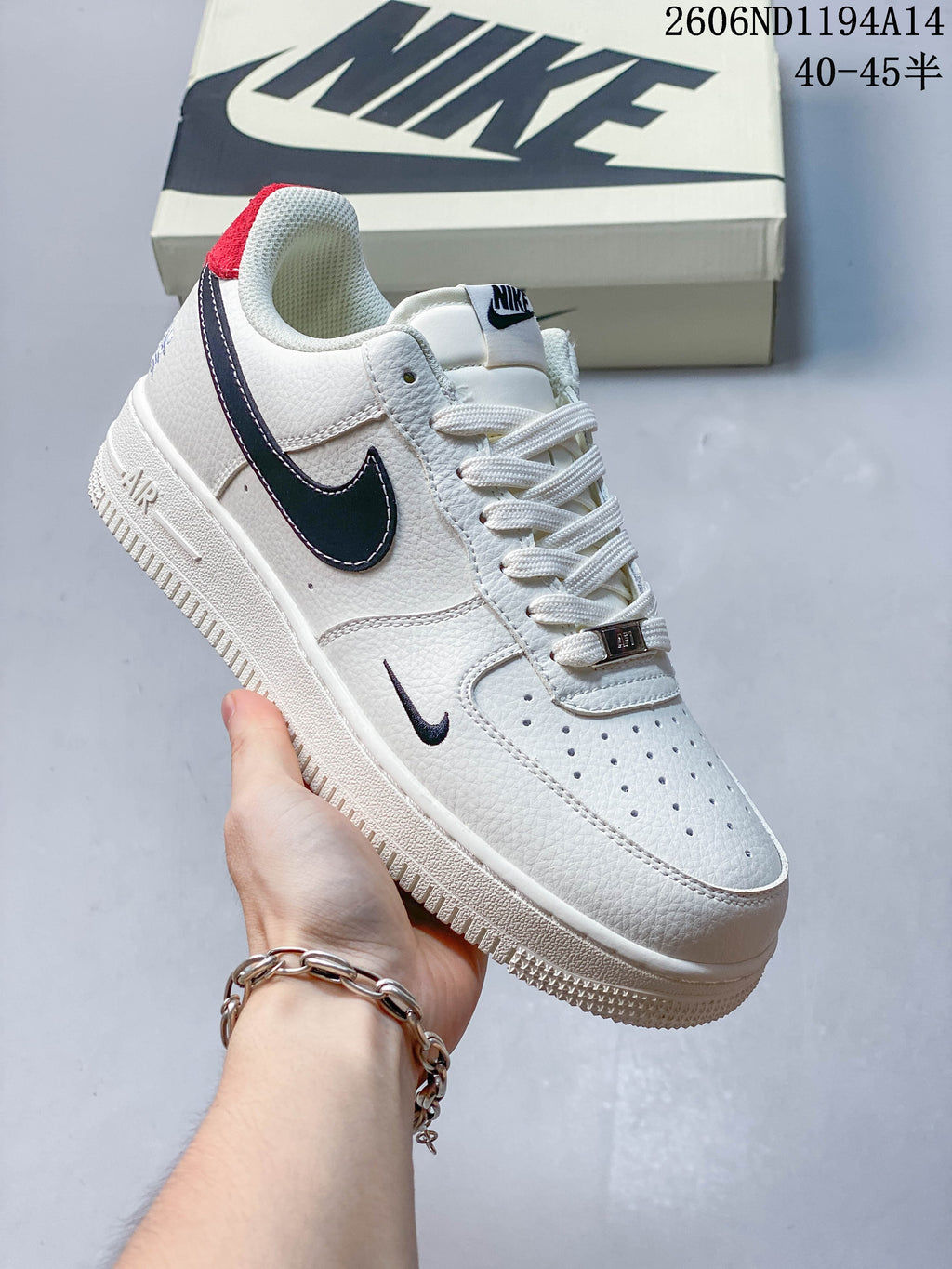 Angled side view of the white low-top sneaker with navy Swoosh and red heel accent