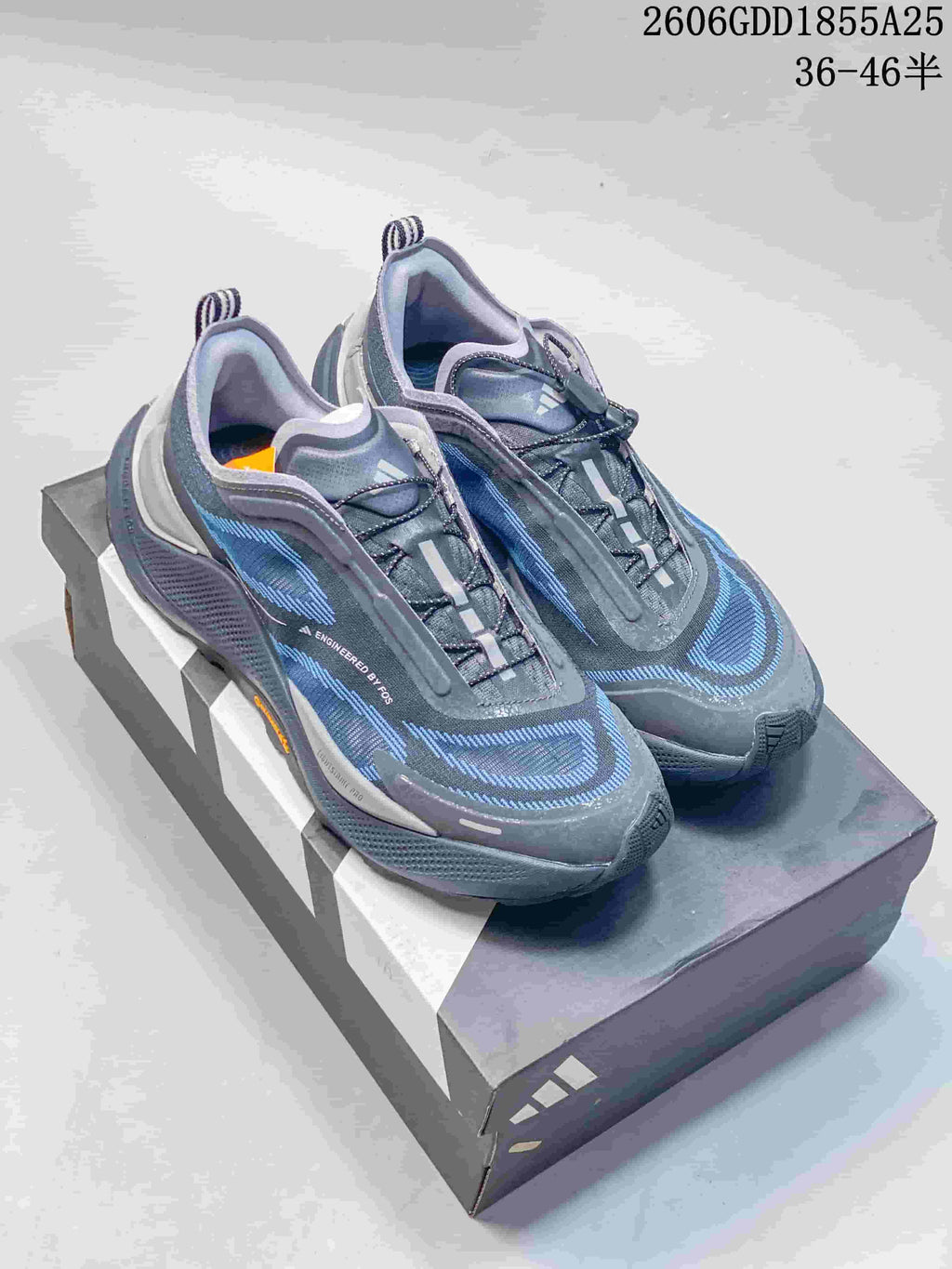 Pair of dark gray Adidas Holo Peak shoes with blue detailing displayed on a shoebox