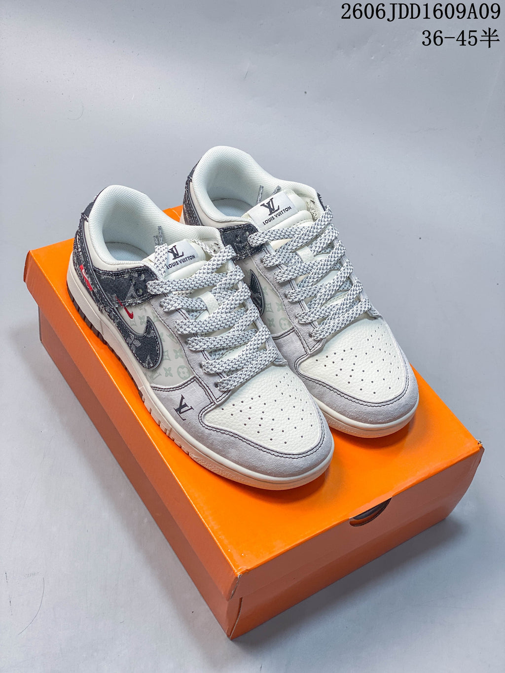 Pair of cream and gray low-top sneakers with printed panels and dark patterned Swooshes, shown on an orange box
