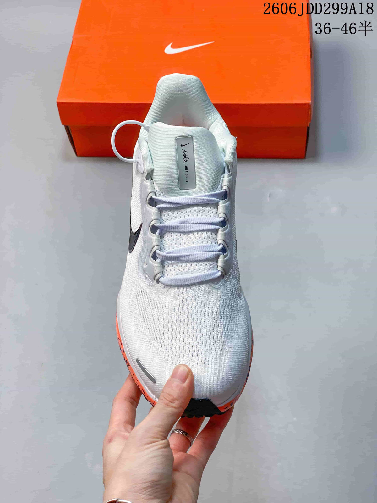 Front view of a white Nike running shoe with lace-up closure and orange midsole details.