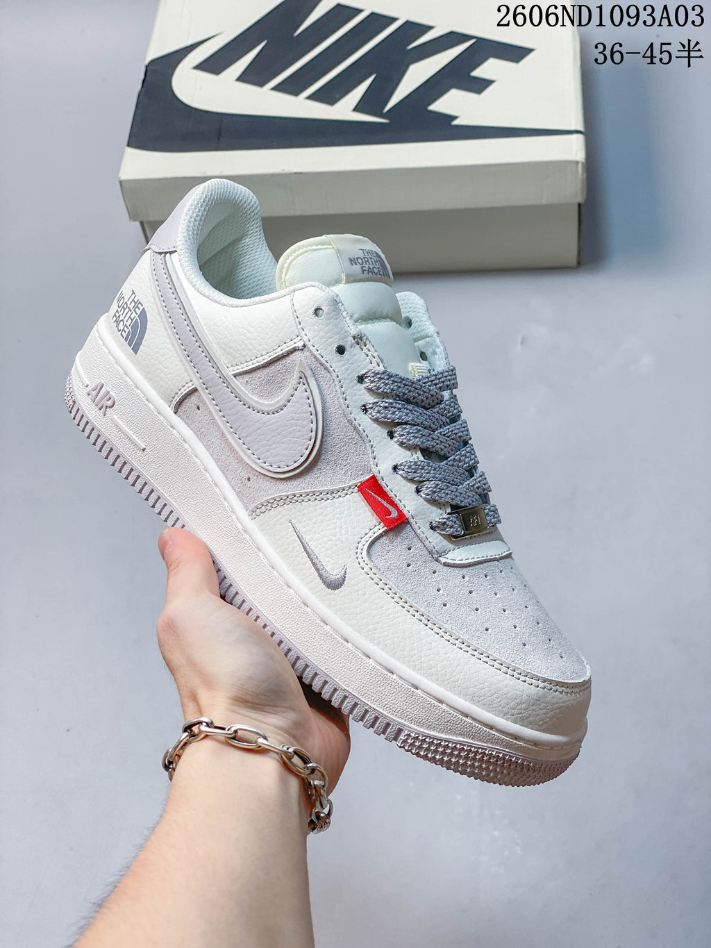Side view of a white and gray low-top sneaker with contrasting laces and red accent tab