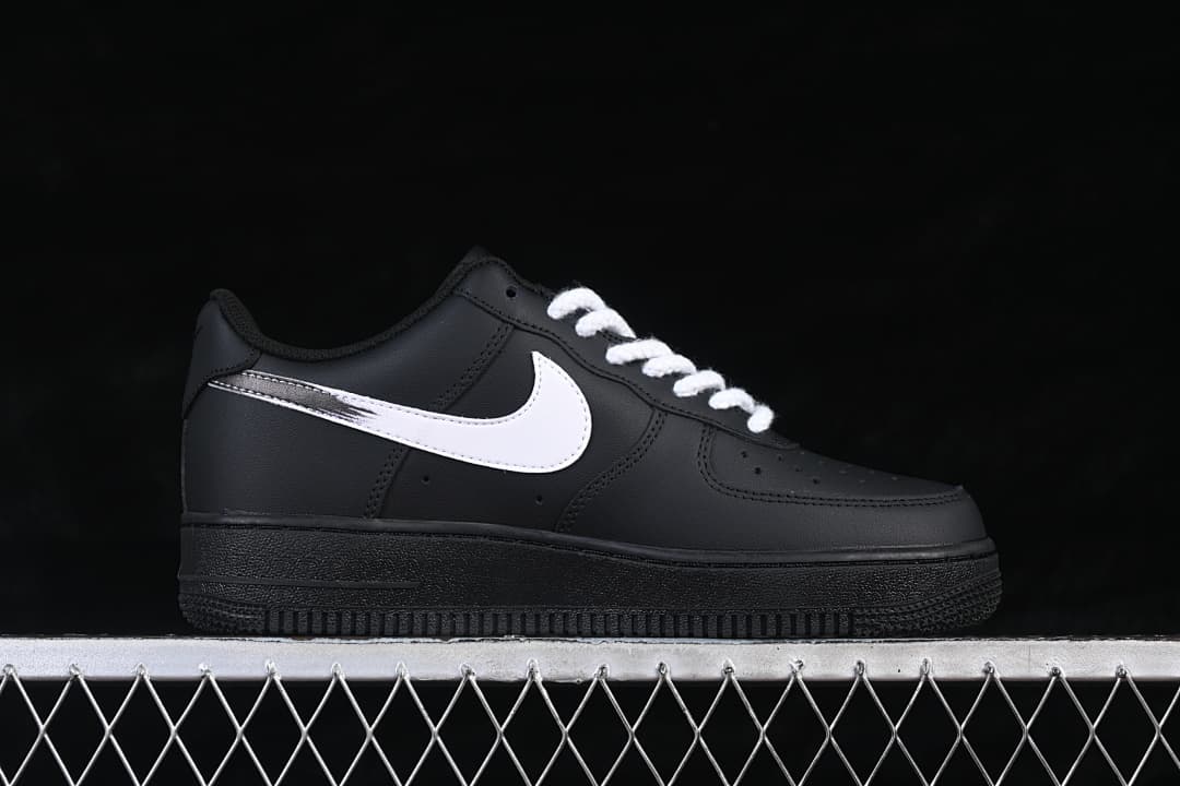 Side view of the black low-top sneaker with a white Swoosh and white laces
