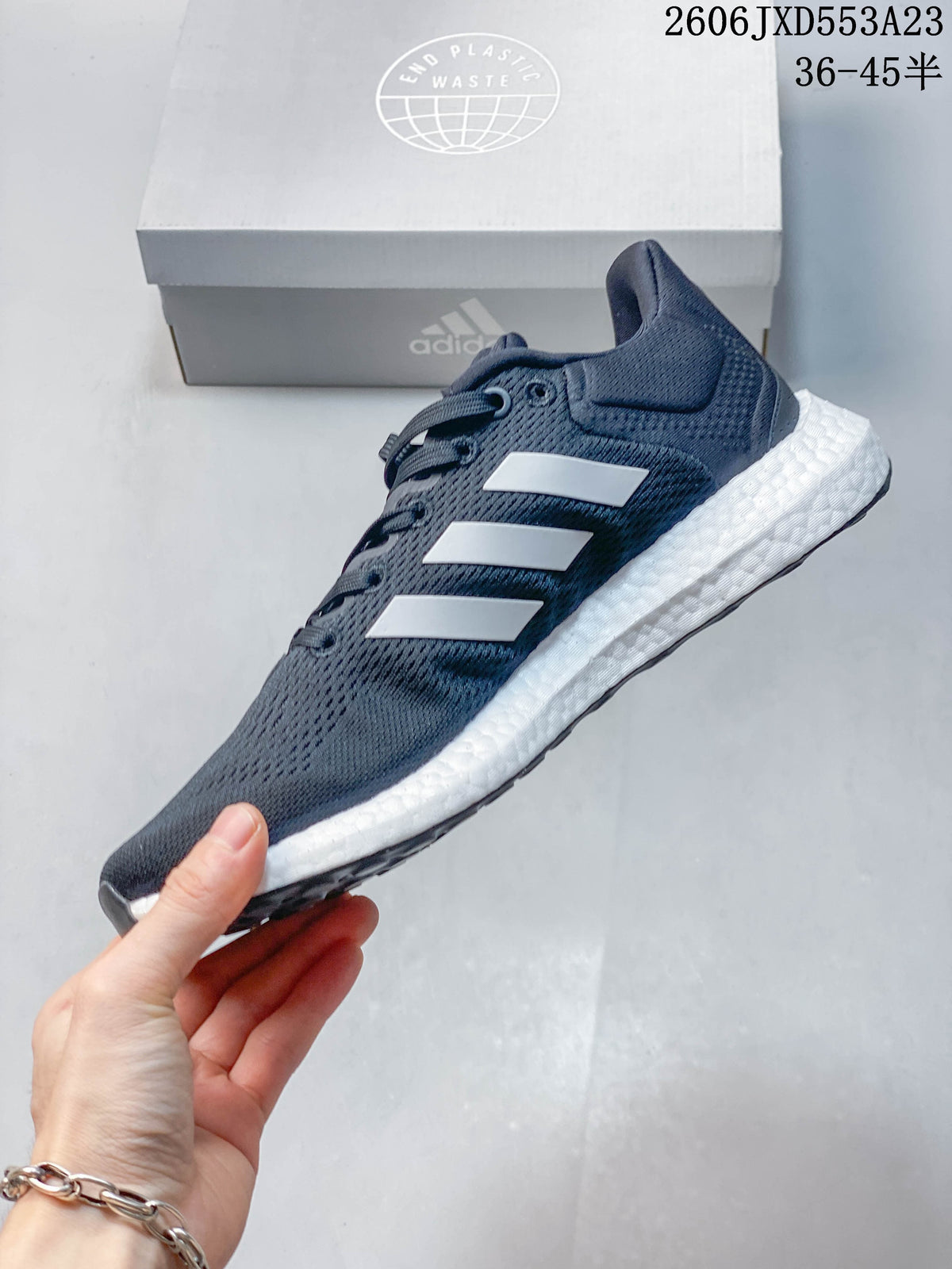 Side profile of a navy Adidas PureBoost 21 running shoe with white stripes.