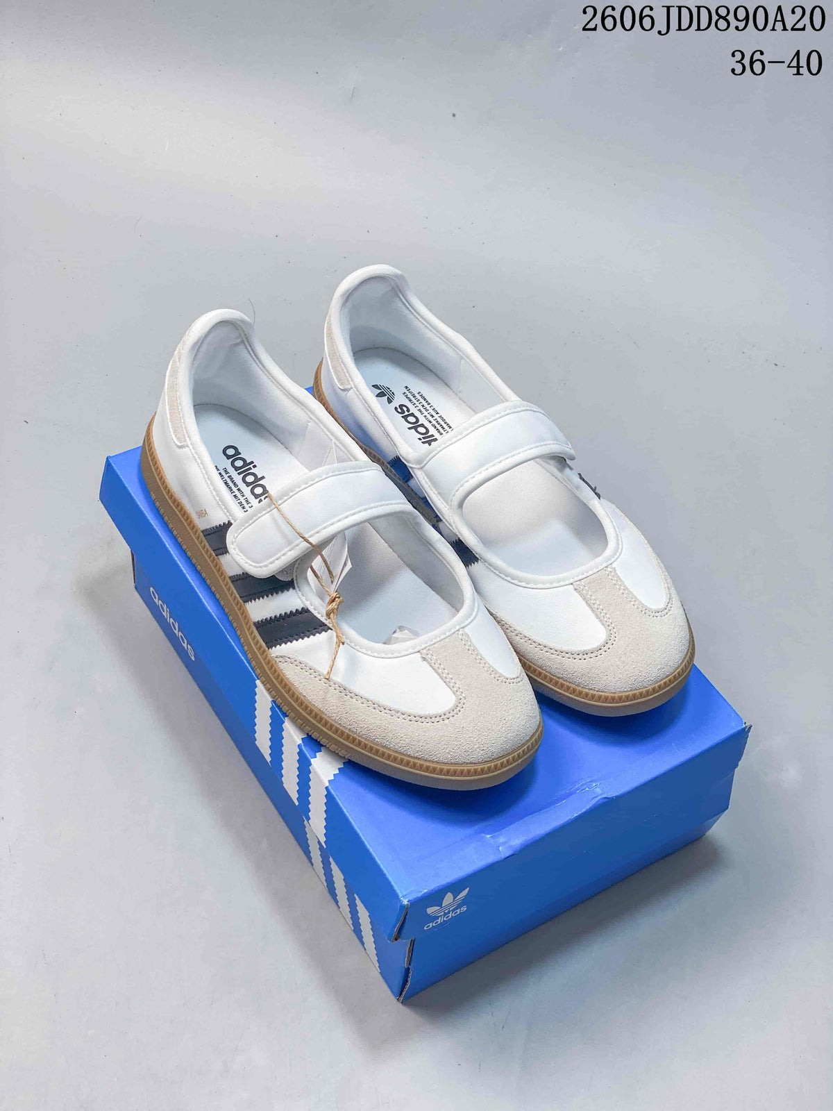 Pair of white adidas Samba Jane shoes with dark stripes, strap closures, light toe overlays, and gum-colored soles.
