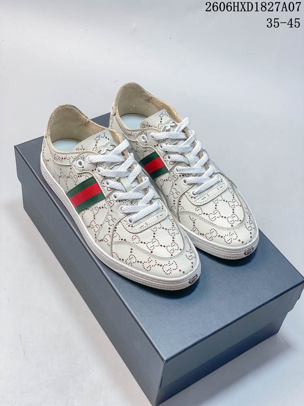 Pair of white perforated low-top sneakers with white laces and green-and-red side stripes