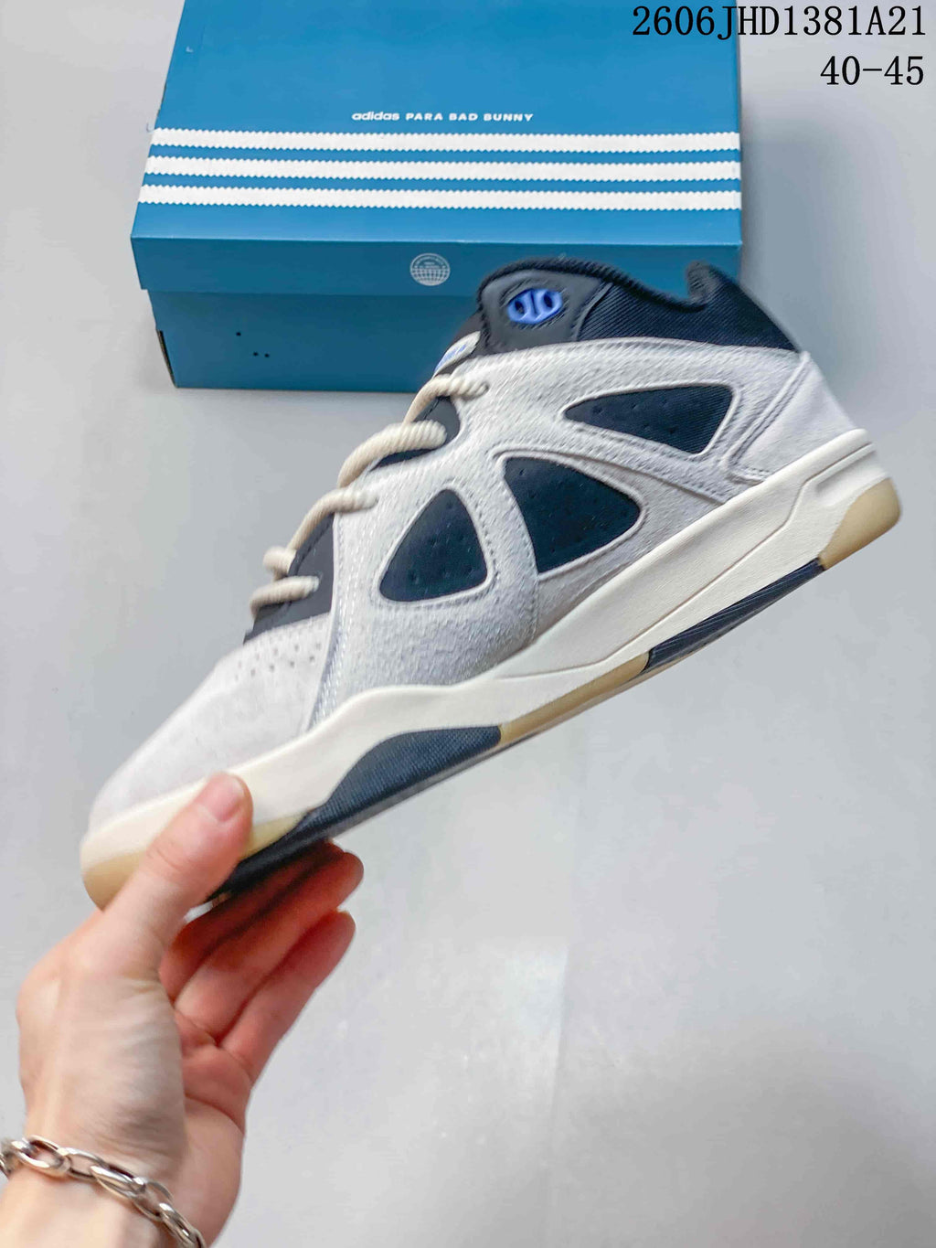 Side profile of the grey and navy high-top sneaker beside its blue box