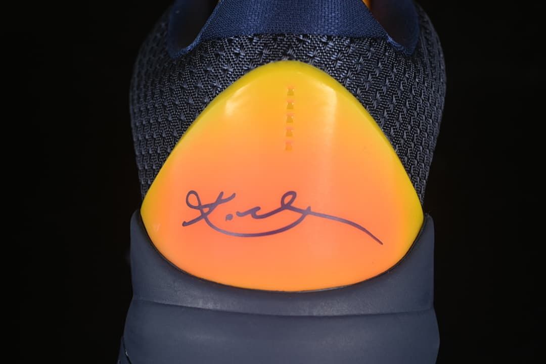 Rear view showing the yellow-orange heel panel and signature-style graphic.