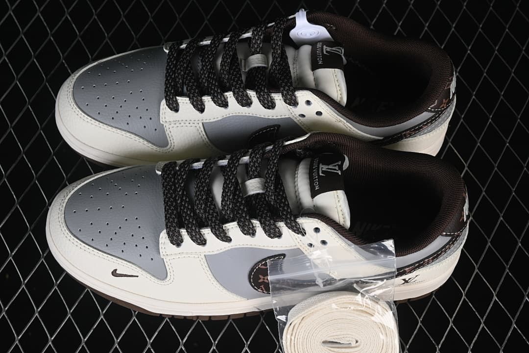 Top view of a pair of white and gray low-top sneakers with black laces and extra white laces shown in a bag.