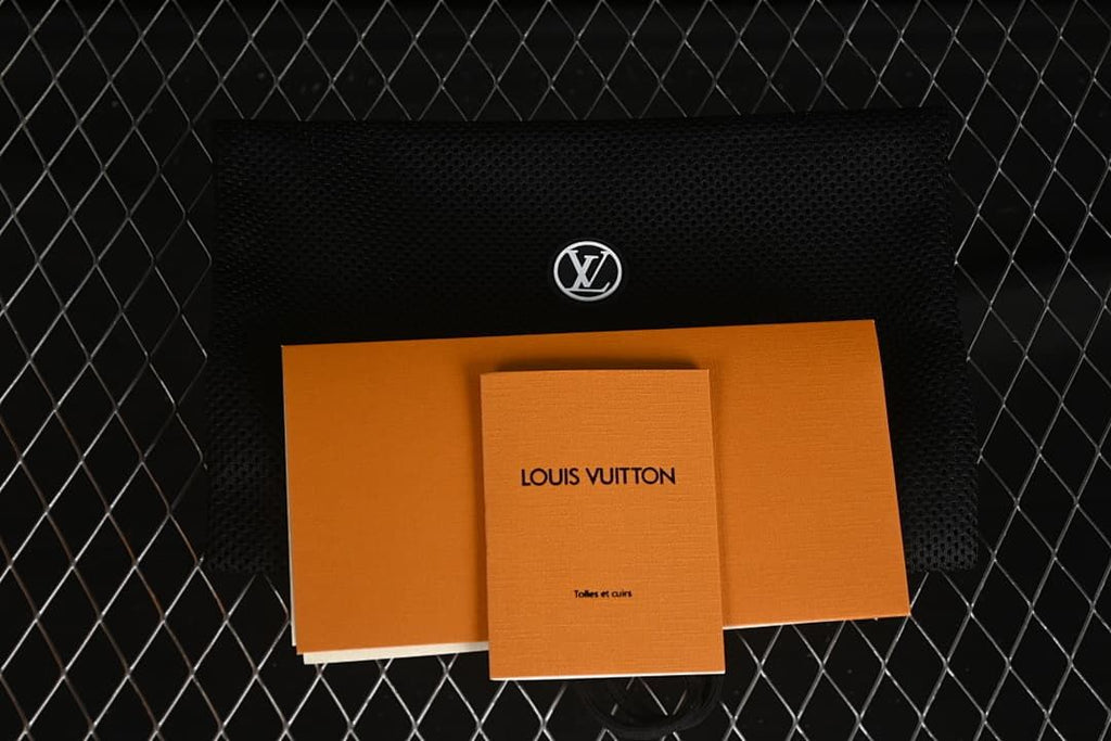 Louis Vuitton-branded packaging and booklet displayed with a black dust bag