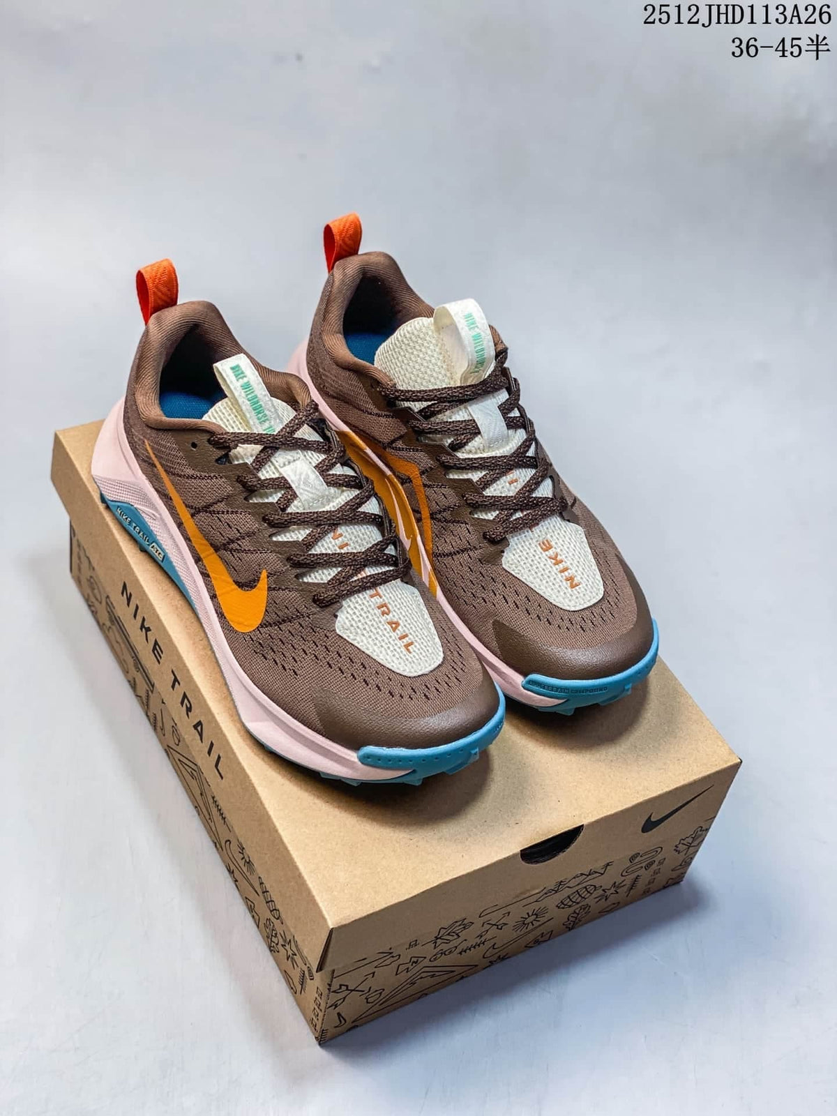 Pair of brown Nike ReactX Wildhorse 10 trail-running shoes with orange, blue, and pale pink accents on a shoebox.