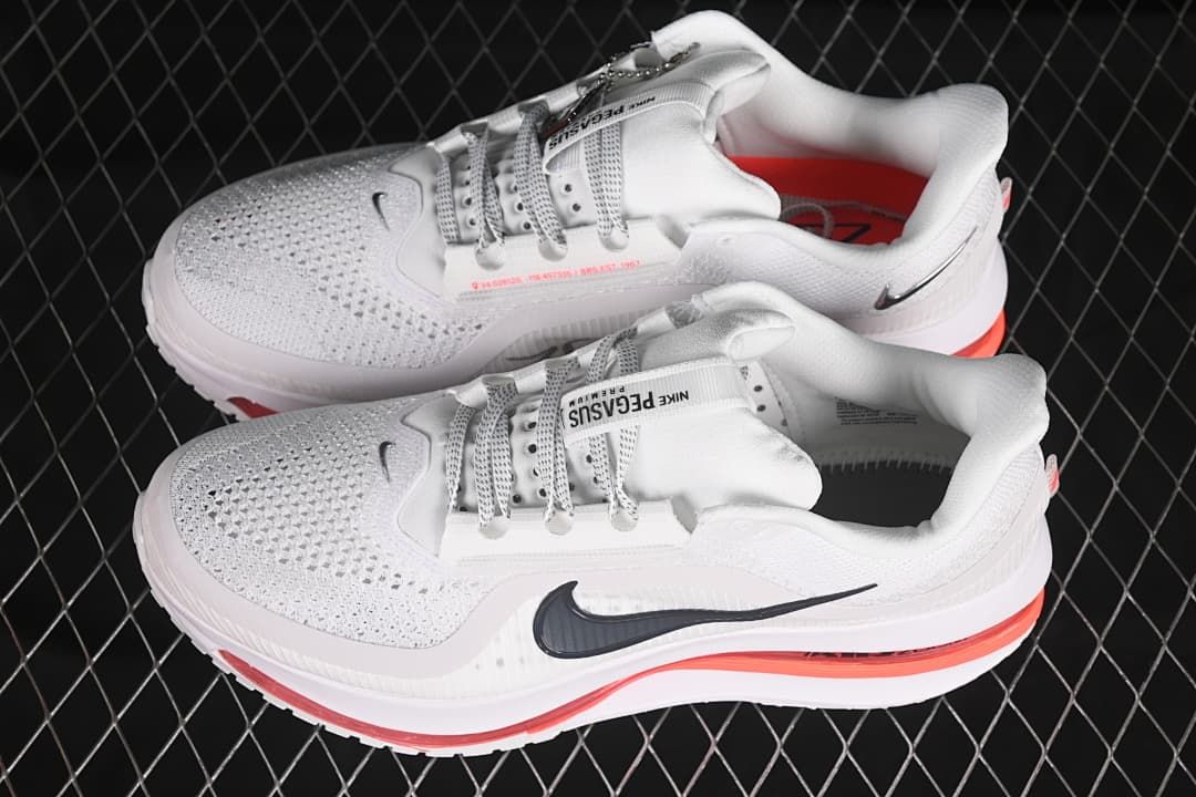 Pair of white running shoes with dark Swoosh details and red accents.