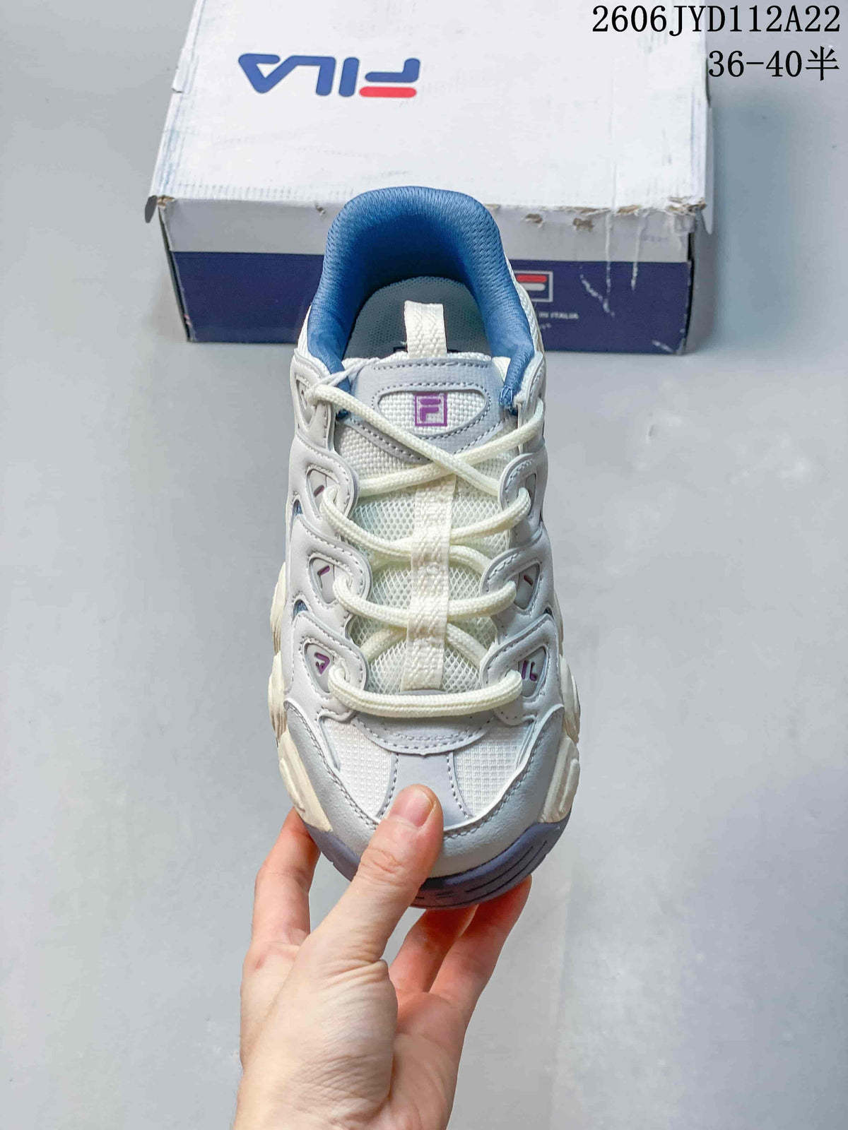 Top view of a white and blue FILA sneaker with white laces and purple accents