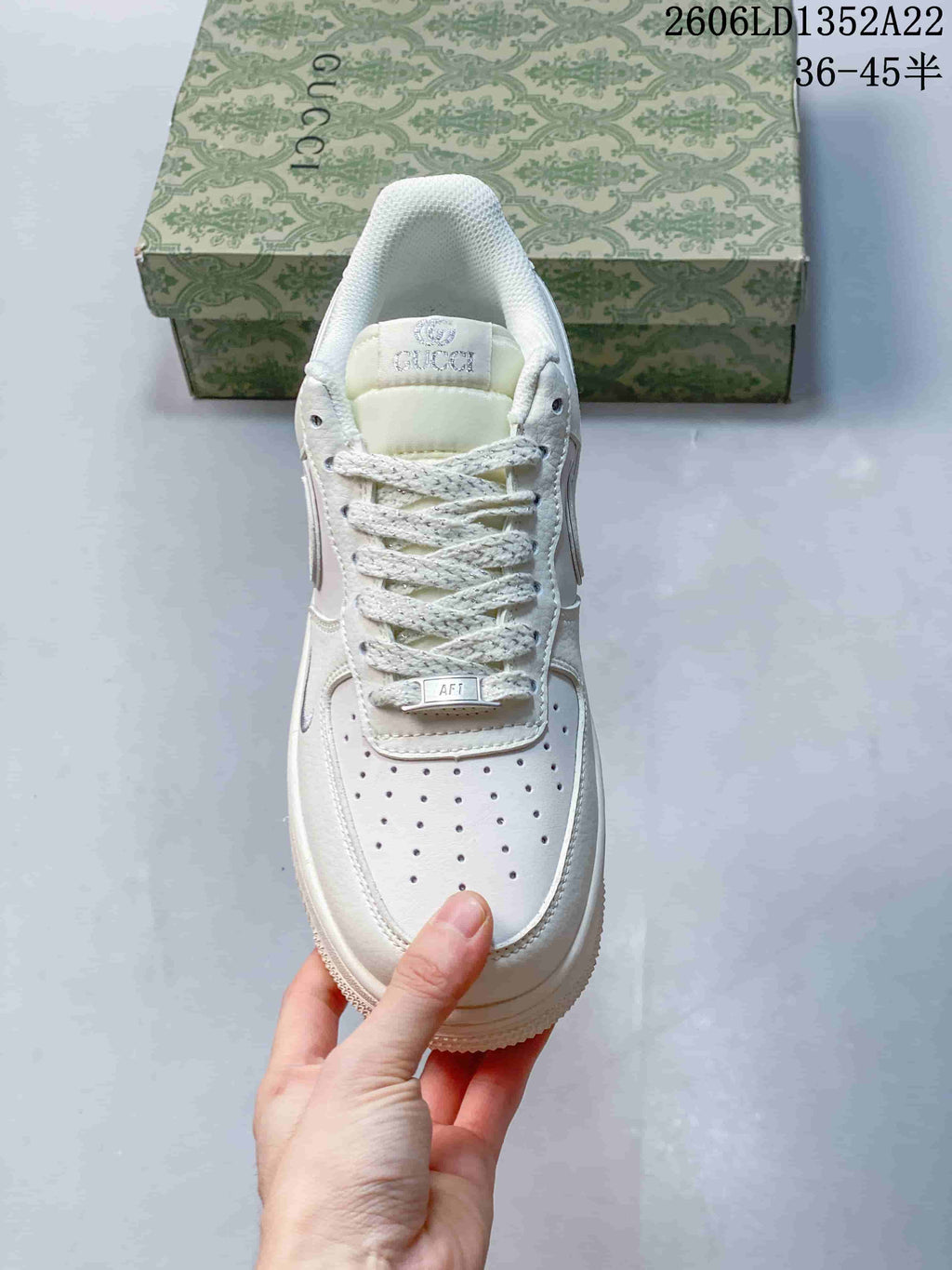 Top-down view of the white sneaker showing perforated toe, laces and tongue branding.